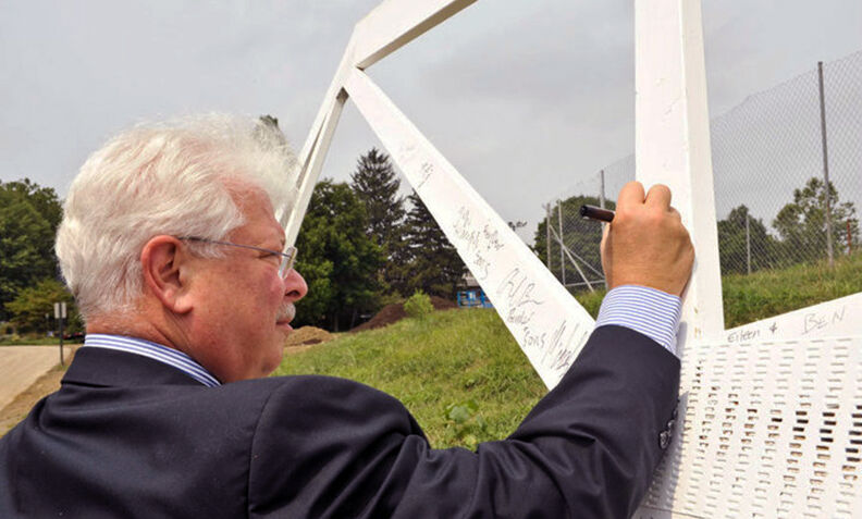 Former Interim President John F. Burness '67 signs a beam during a ceremony marking the construction of New College House (now Roschel College House) in 2010.