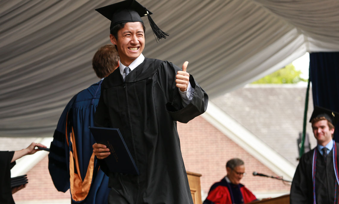 Peter Sun gives the thumbs up to family and friends after receiving his diploma.