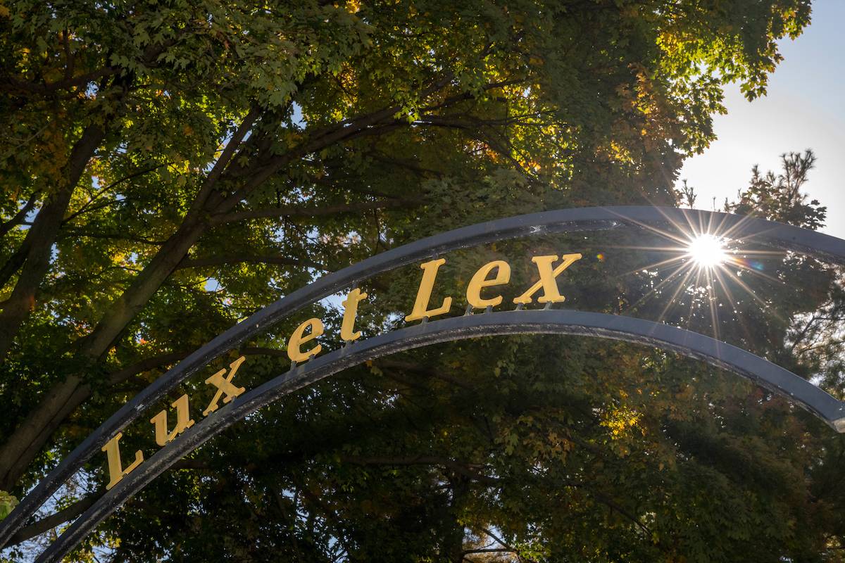 The words Lux et Lex in a metal arch with sun streaming through. 