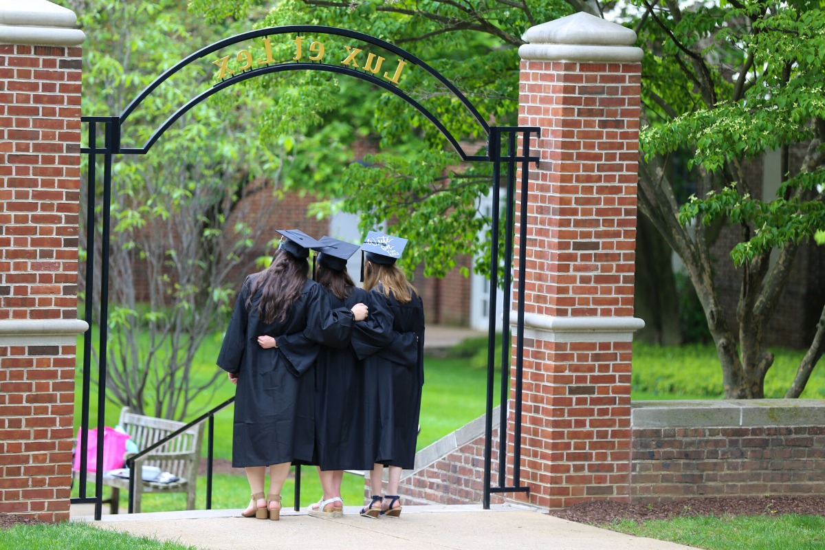 F&M graduates standing beneath the Lux et Lex arch