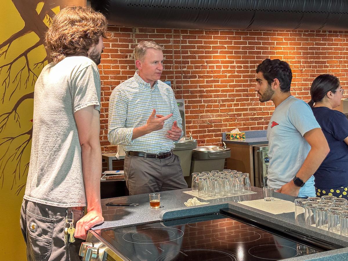 Brewing science student Mark Curi ’27 (right) talks to F&M President Andy Rich about his beer samples at an Aug. 4 tasting.