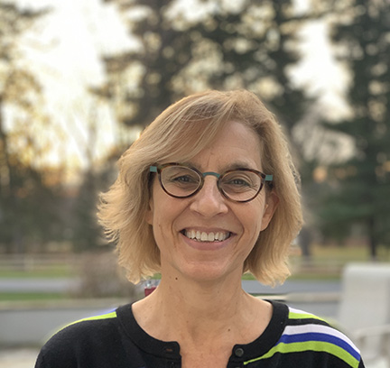 A photo of Nancy Kurland in front of some trees. 