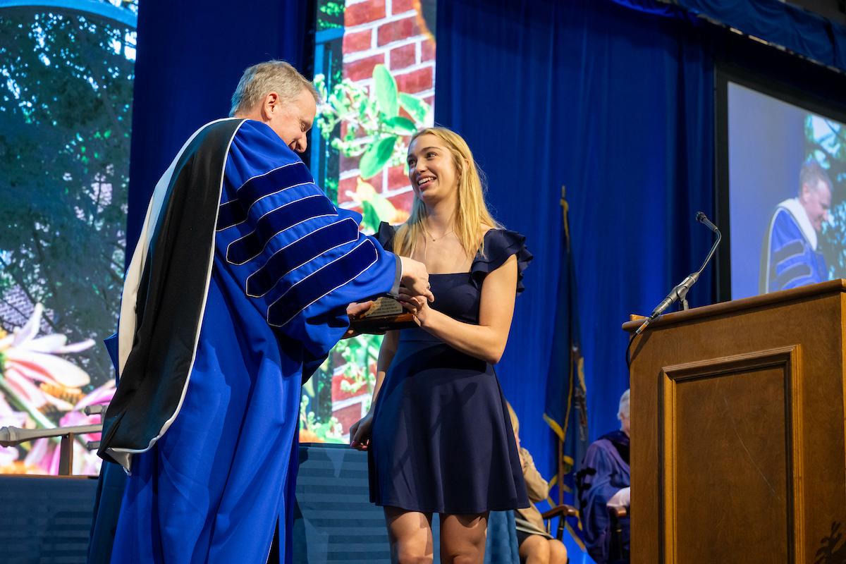 Caroline Riegel ’26, student body president, presents President Rich with a desk clock from the student body. (Photo by Deb Grove)