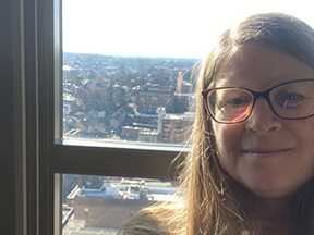 Melissa stands in front of a window overlooking the city of Lancaster, PA