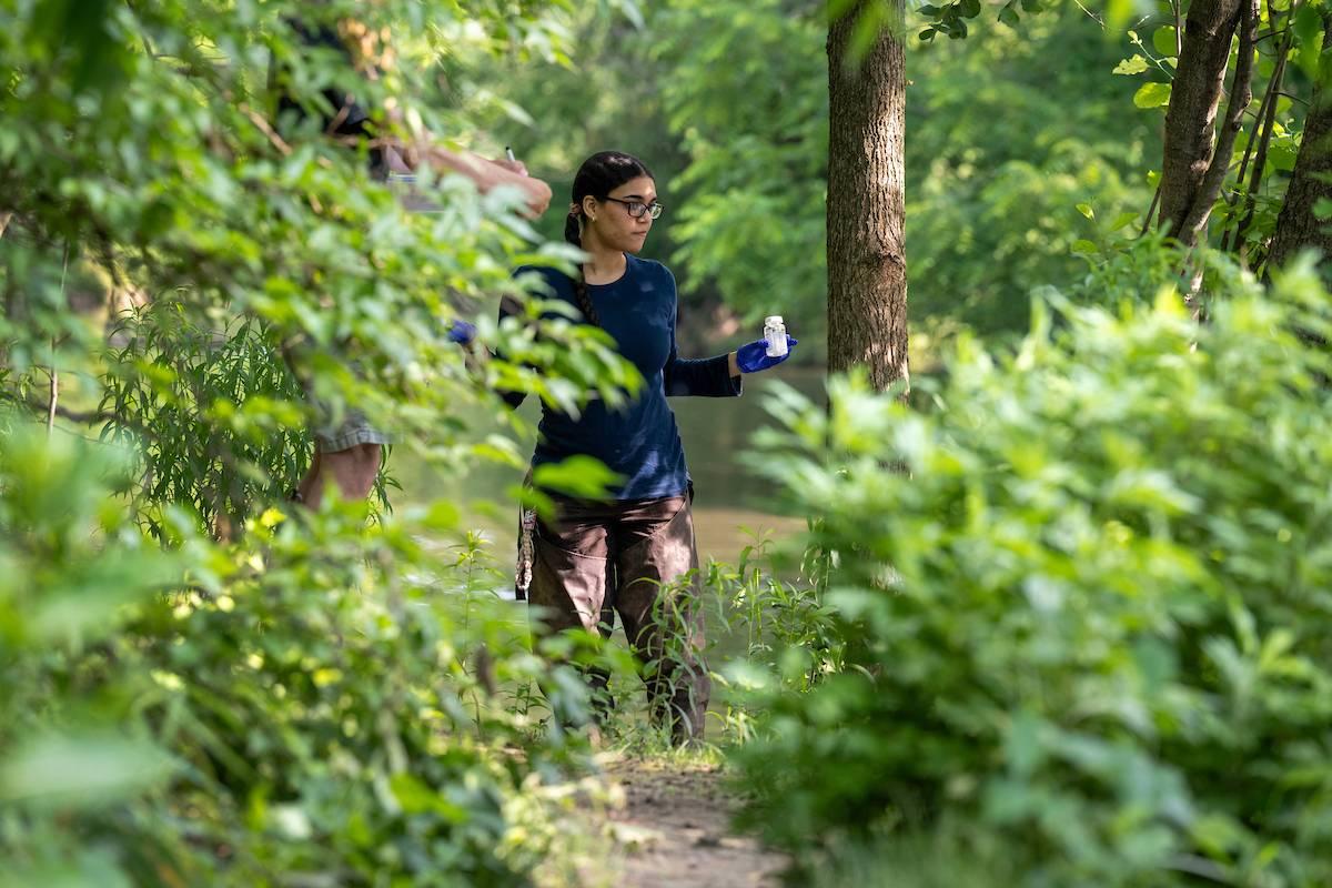 Roselyn Ovalles ’26 stands alongside a river surrounded by trees and bushes.