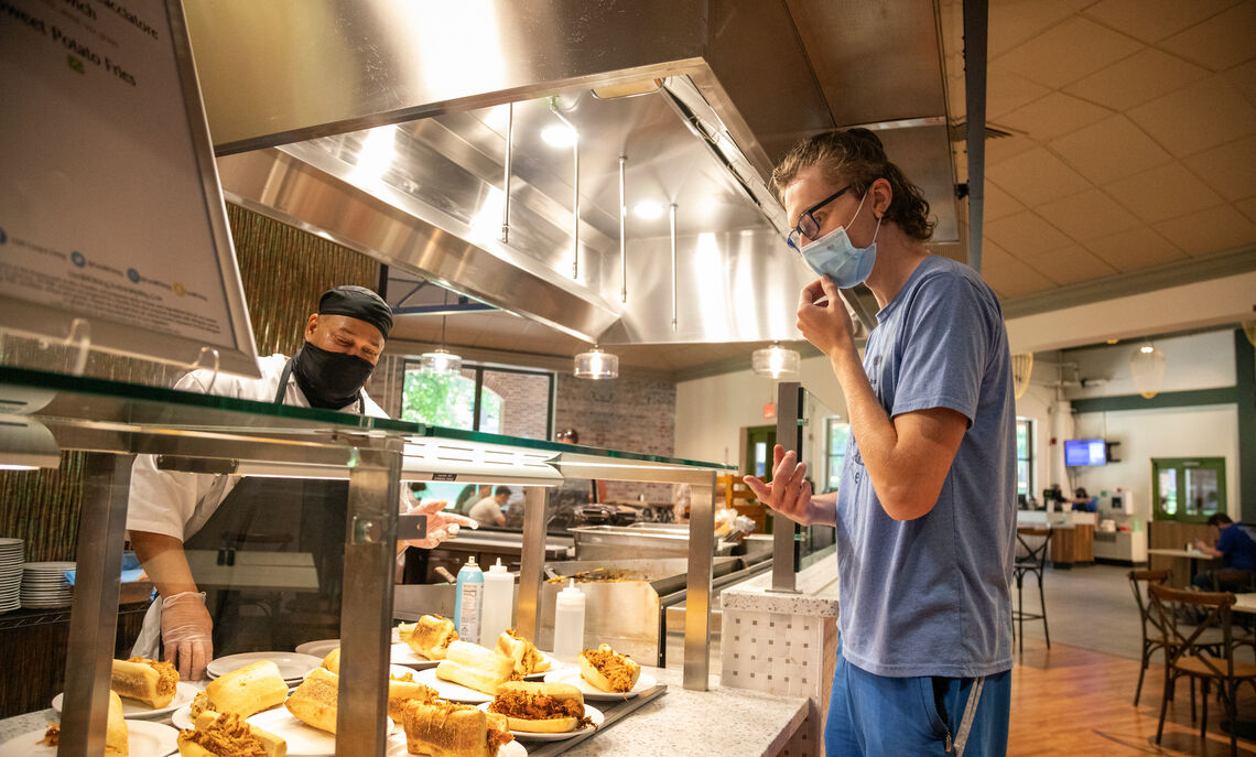 A chef lines up plates of freshly made pork BBQ sandwiches for diners.