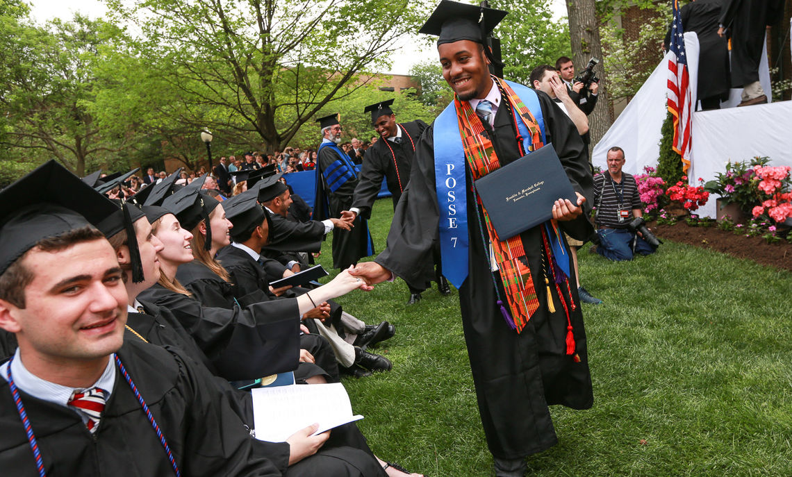 Keiran Miller gets a congratulatory handshake as he makes his way off the Commencement stage.