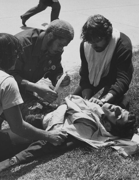 An injured person, John Cleary, being given first aid, near the campus' Don Drumm sculpture.