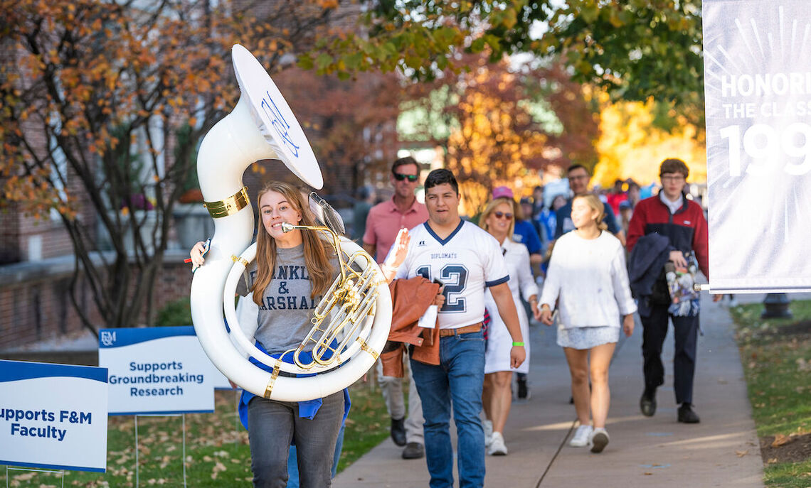 The F&M pep band leads the Williamson True Blue Tailgate crowd toward Shadek Stadium.