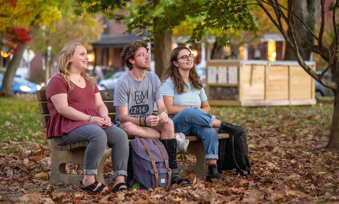 Caroline Kleis '24, Bennett Wasch '23, and Athena Kotsopriftis '25 discuss their involvement with Lancaster Composting Co-Ops. The Buchanan Park compost bin can be seen in the background.