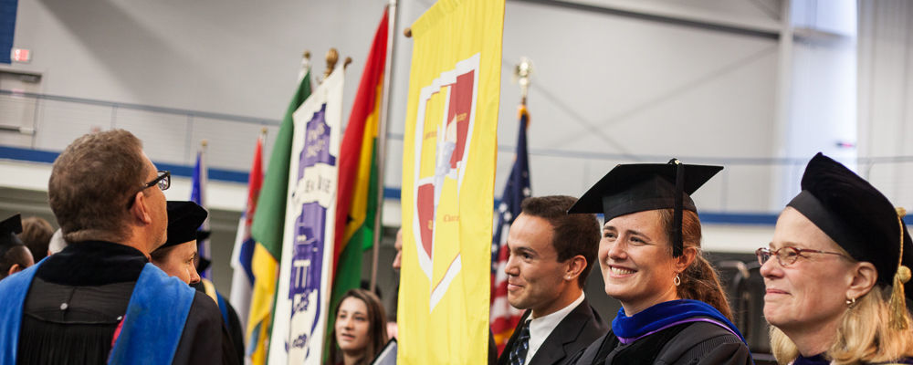 

	College House leaders holding flags of their House crests, along with members of the faculty, process during Convocation. (Photo by Melissa Hess)