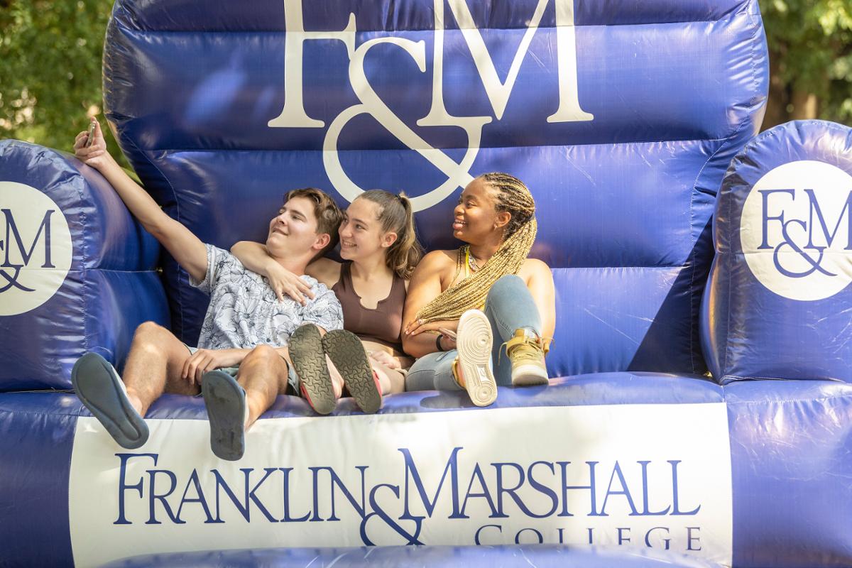 Students posing on F&M chair