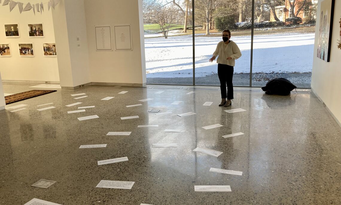 ... Senior Michele Jacobs before the tiles of quotes taken from several years of student interviews with refugees and immigrants who came to Lancaster.
